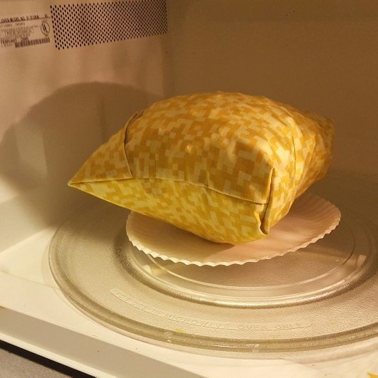 microwave popcorn bag puffed up with popped kernels inside a microwave on a plate