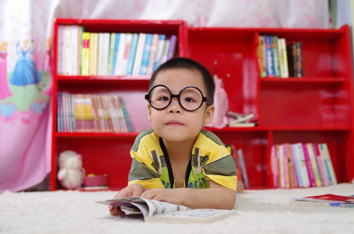 little boy reading glasses books bookshelf child learning child development