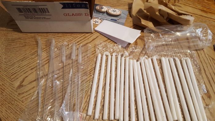 USPS package with glass straws straw cleaning brushes packaging materials next to it