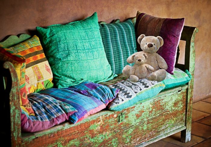 an upcycled antique bench with destressed look painting and pillows and teddy bears