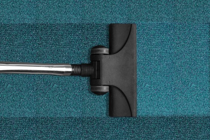vacuum nozzle on teal carpet The Health Benefits Found in a Clean Home 