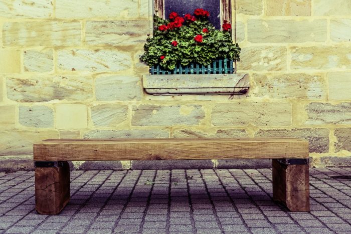 wood bench flowers in window brick wall 
