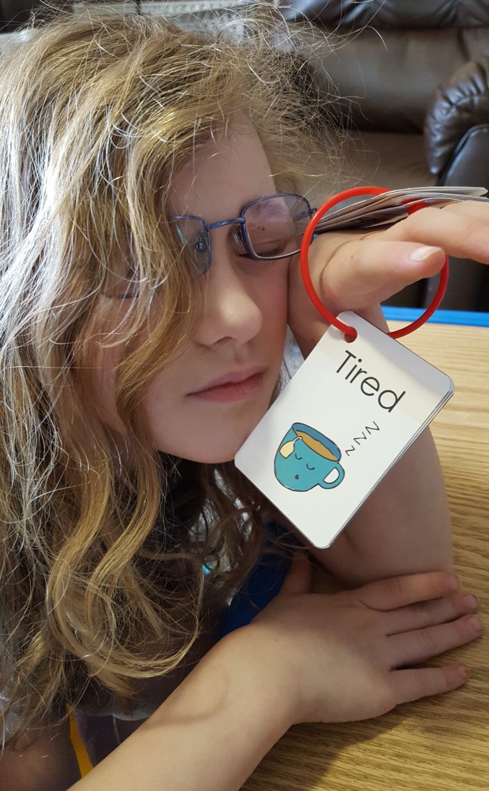blond curly hair girl glasses pretending to be asleep holding tired feeling card from haley sez