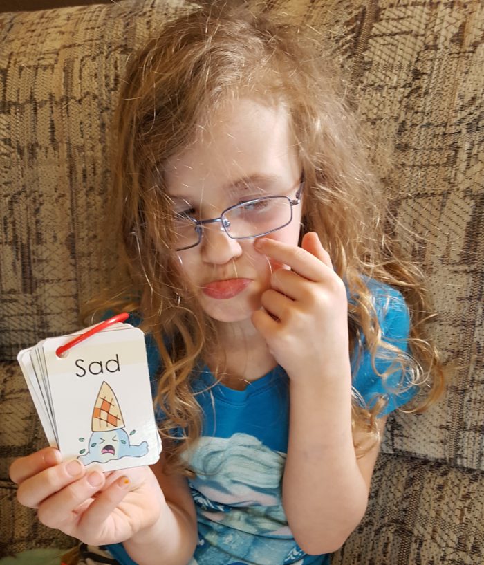 young girl with messy hair glasses showing the feeling sad and wipes invisible tears Haley Sez feelings flipper cards