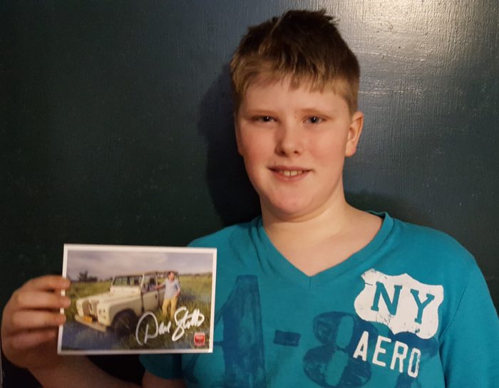a pre teen boy holding an autograped picture of Dave Stotts from Drive Thru History Adventures