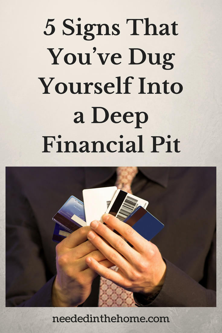 5 Signs That You’ve Dug Yourself Into a Deep Financial Pit man holding credit cards fanned out neededinthehome
