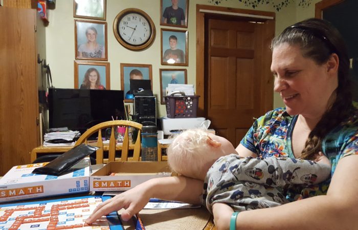 review of Goliath Games Smath board game mother holds sleeping toddler boy while playing board game