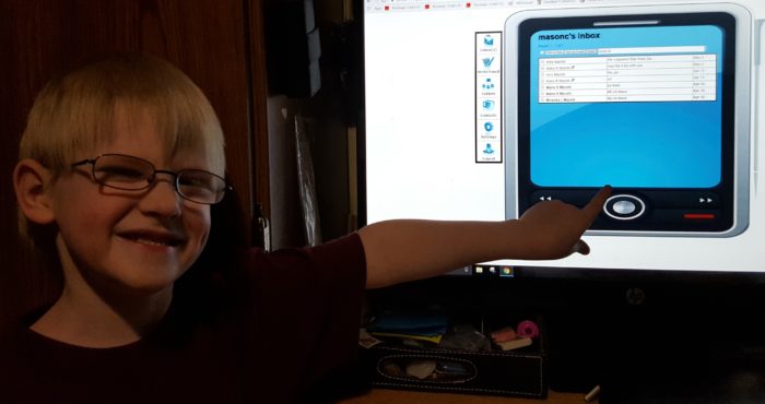 Kids Email review image of a young blond boy in glasses pointing to the email messages he received on a computer screen