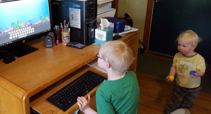 Review of ASD Reading computer program for autism spectrum disorder image of boy using computer with toddler boy holding balls watching his brother