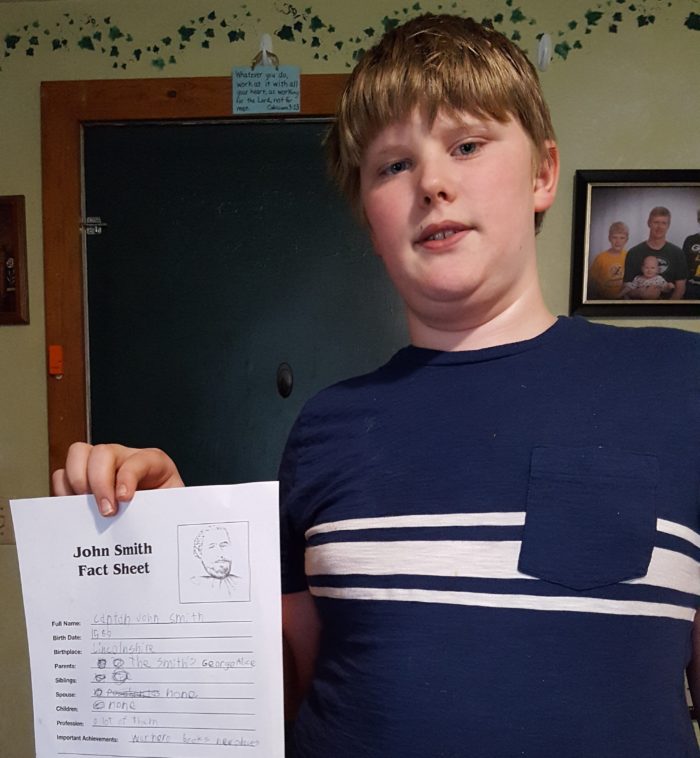 Captain John Smith preteen boy holding up his fact sheet worksheet he is working on from a unit study
