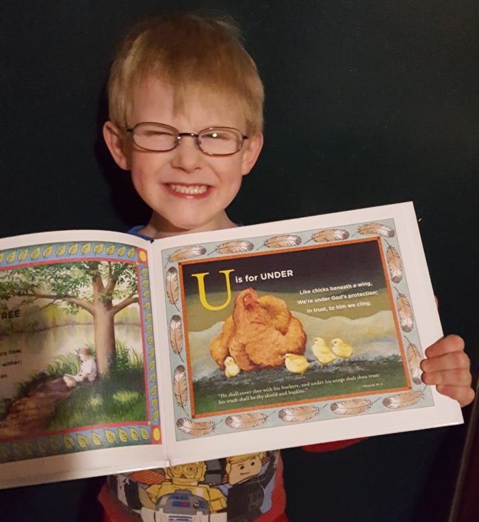 T is for Tree Book Review image boy in glasses and big smile holding book with U is for Under page showing