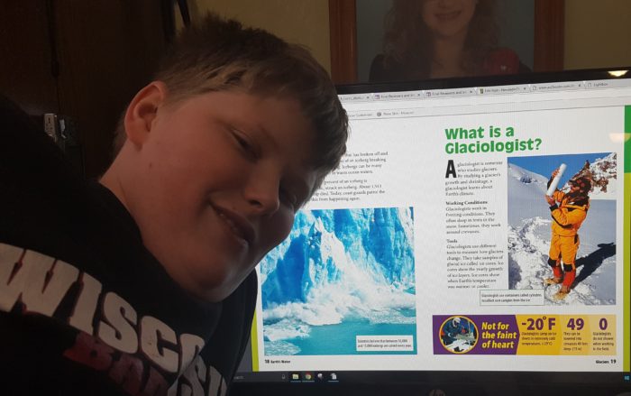 Weigl Publishers Glaciers Interactive Electronic book on the computer screen with a pre teen boy next to it