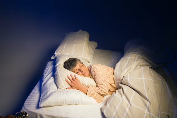 Better night's sleep image woman sleeping in bed at night with pillows and blankets