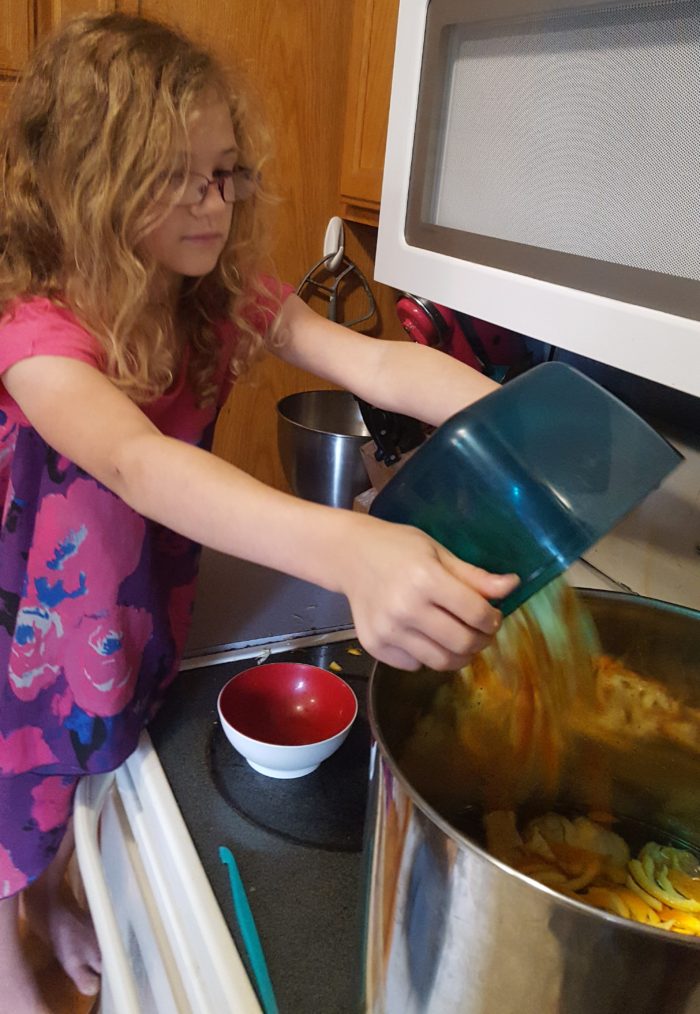 Paddington Bear Literature Based Unit Study girl dumping cut orange peels into pot of marmalade mixture