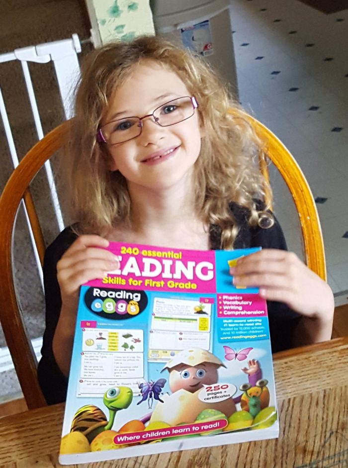 Reading Eggs workbook review first grade second grade girl in glasses smiling holding workbook