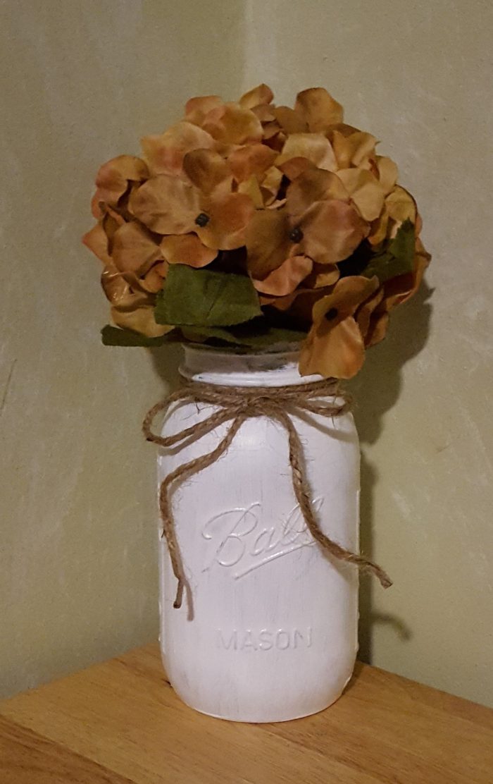 Mason Jar Crafts white painted ball mason jar tied with jute twine filled with beige hydrangea flowers