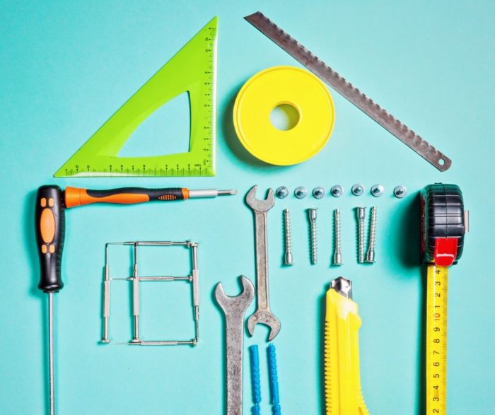 Important home improvements tools arranged in the shape of a house that needs repair