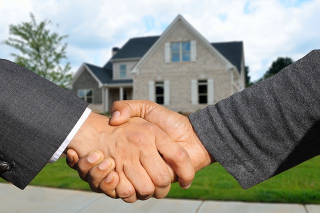 Hire when moving men shaking hands in front of sold house