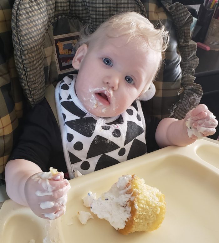 feeding bibs with snaps blond blue eyed baby girl messy with her smash cake one year old birthday girl in bib