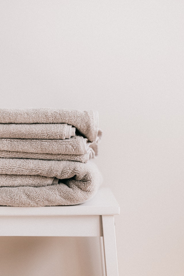 dreary bathroom pile of towels on wooden table