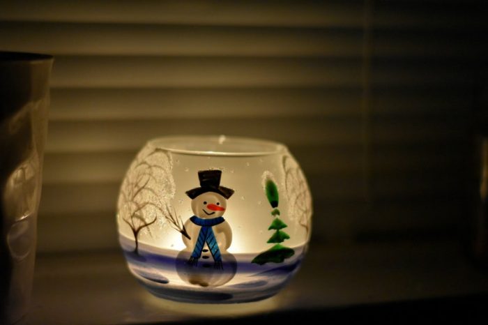 snowman bathroom sets lit candle in a dark bathroom with happy snowman shining on the candle's side