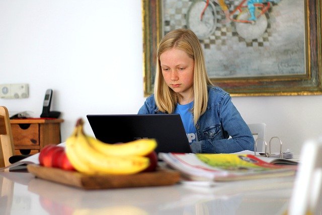 pinterest-pin-description 5 activities that complement your homeschool curriculum girl doing homework on laptop kitchen table bananas