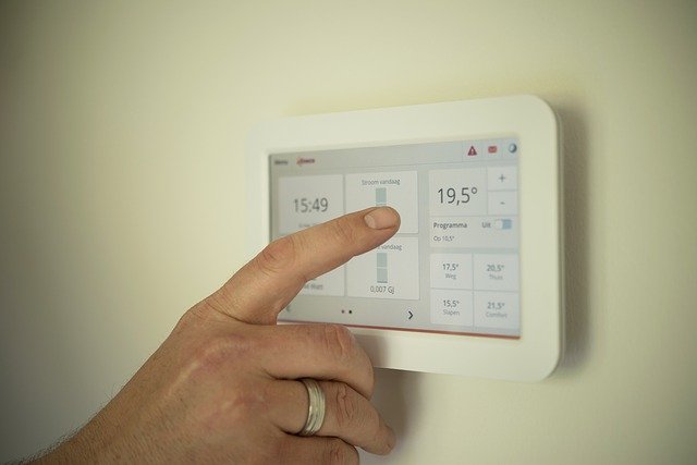 saving on household bills man's finger about to push thermostat to change temperature