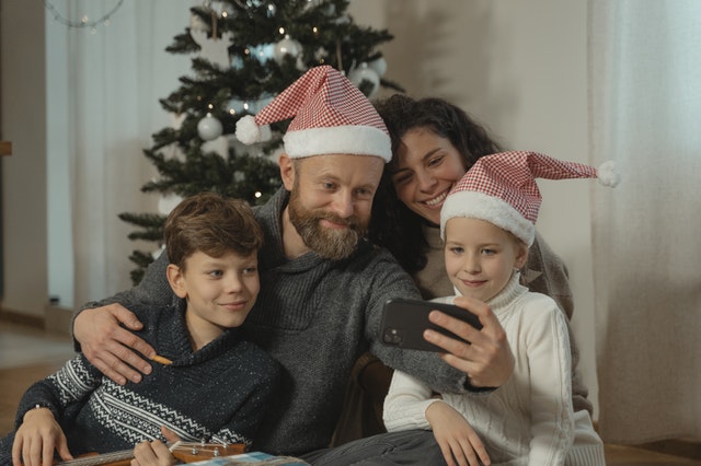 new year's resolutions for parents family of four taking selfie in front of christmas tree
