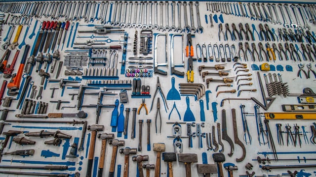 diy tools nicely organized on a wall with pegs and shadows painted blue so you know where to put them