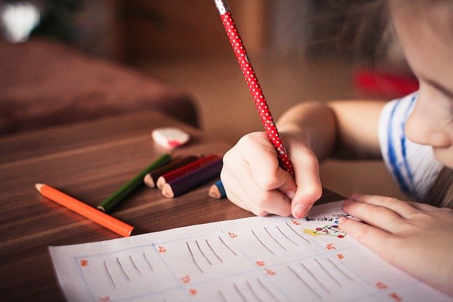 ensure child succeeds child holding pencil writing on an activity sheet