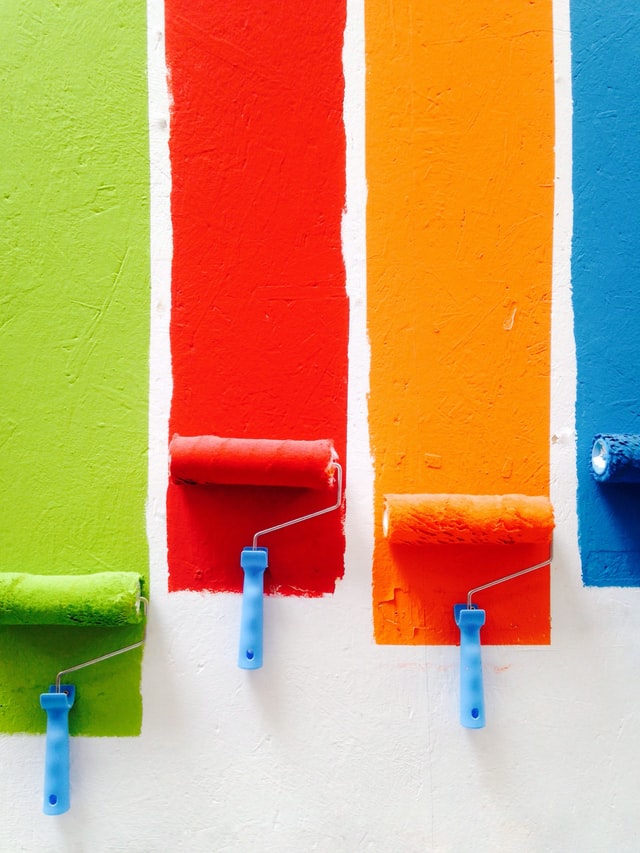 revamp your home effortlessly four rollers of paint with paint on wall above each in colors green red orange and blue