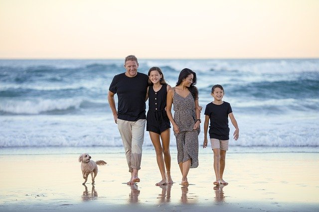 healthy family goals father mother daughter son dog walking on beach near ocean water waves