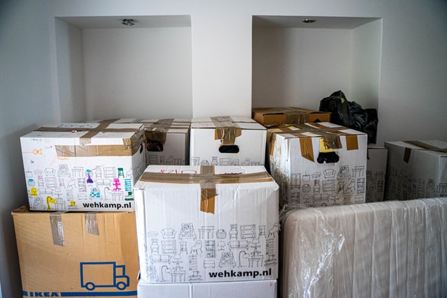 pack furniture for moving image of a room full of packed and taped cardboard boxes and a sealed mattress