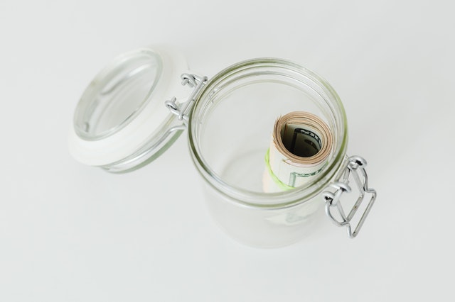 start an emergency fund open glass jar with flip lid roll of dollars inside