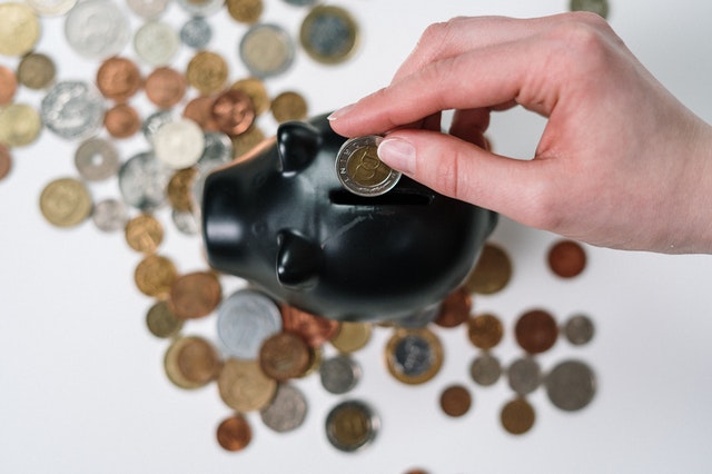 before investing finances piggy bank with coins hand putting coin in the pig
