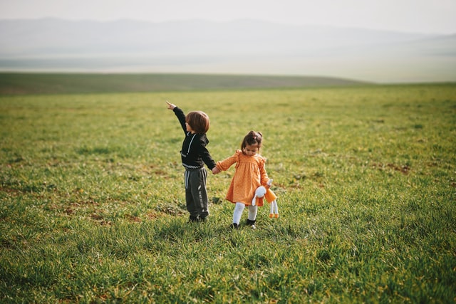 moving with kids less traumatizing boy and girl holding hands in a large empty field