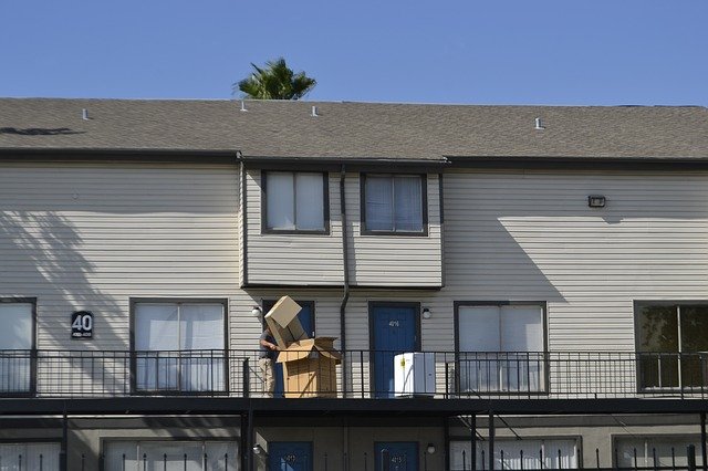 move house less stress man managing empty cardboard boxes on top floor apartment balcony next to washing machine