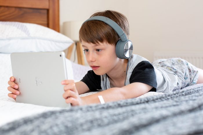 choose tablet for child boy looking at tablet while laying on his bed