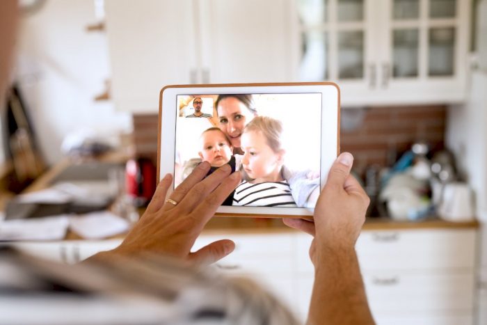 husband looking at wife and two children on ipad screen