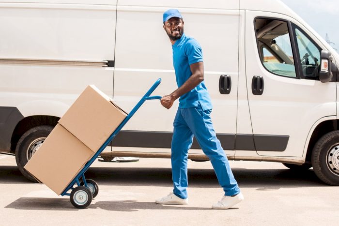 delivery services for business with man pushing cart of shipping boxes next to white van