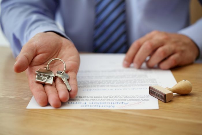 understanding home buying process real estate agent holding keychain with house key next to accepted stamp and paperwork