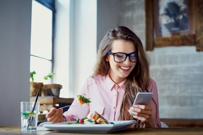 manage business from home woman looking at phone while eating lunch