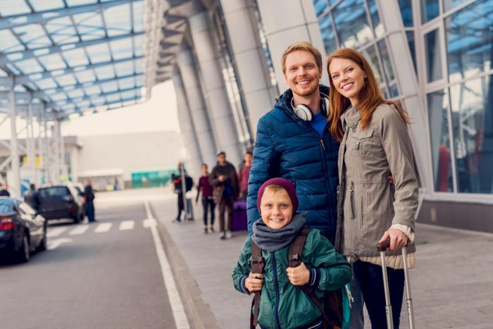 kids educated while traveling family of three smiling standing at airport pick up lane