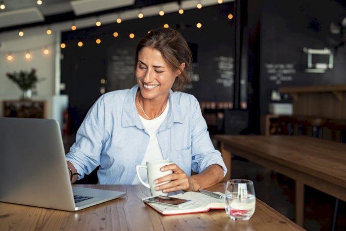 mom friendly careers woman smiling looking at laptop with coffee in hand