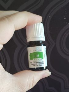 lime essential oil from young living held in a person's finger and thumb