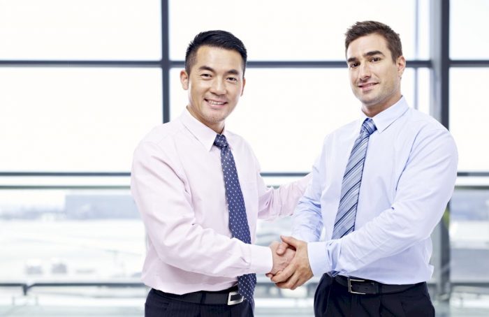 companies reach wide audience two men shaking hands smiling