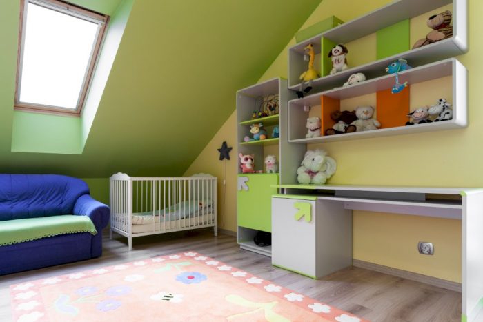attic made into a nursery playroom with couch crib shelves of plush toys with attic rooflight window above couch