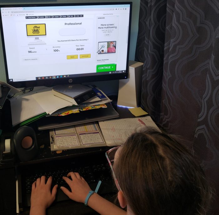 girl doing typing lessons on typedojo sees professional 96 wpm after a typing test on monitor