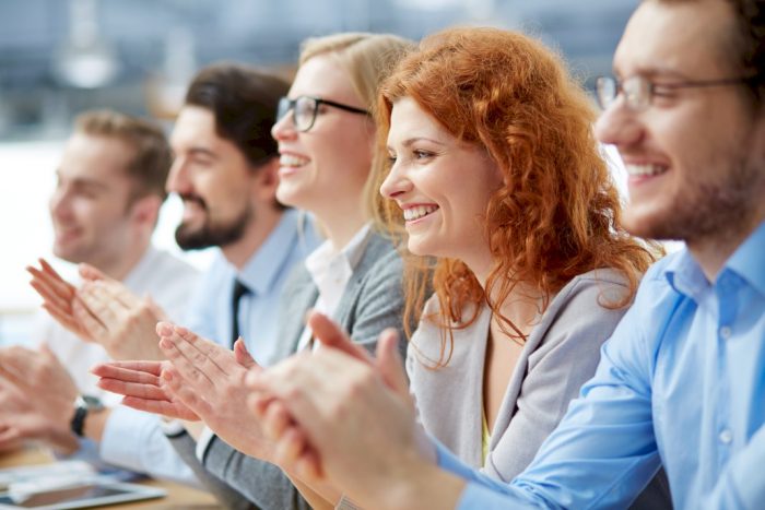 five smiling clapping people after a speaker teaching how to succeed as business women and men
