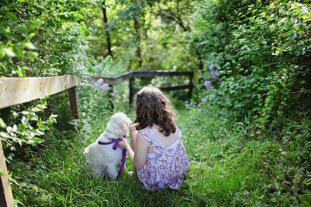 girl and puppy in overgrown grassy area that could use care for the backyard
